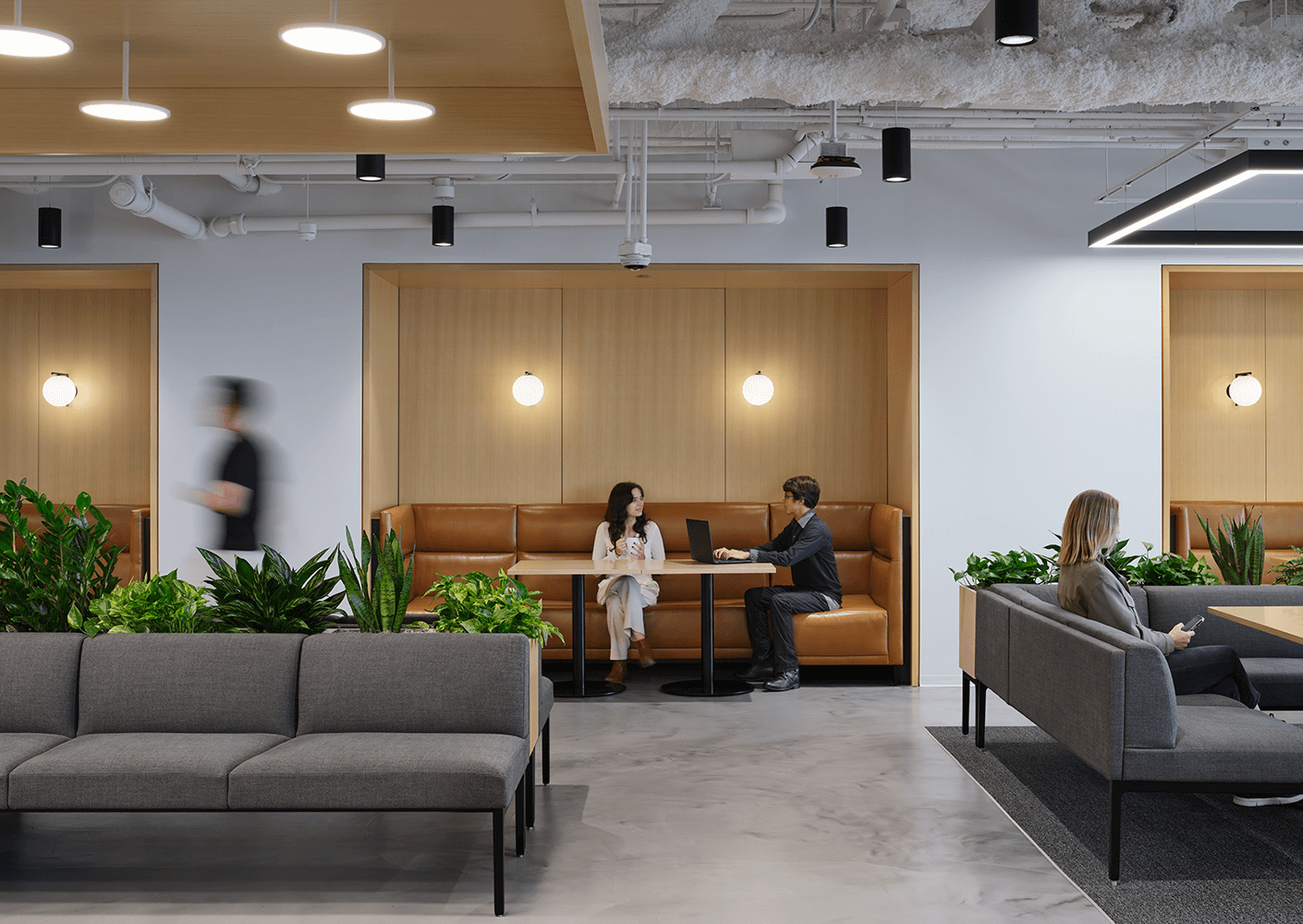 Modern office lounge with people chatting and working on laptops.