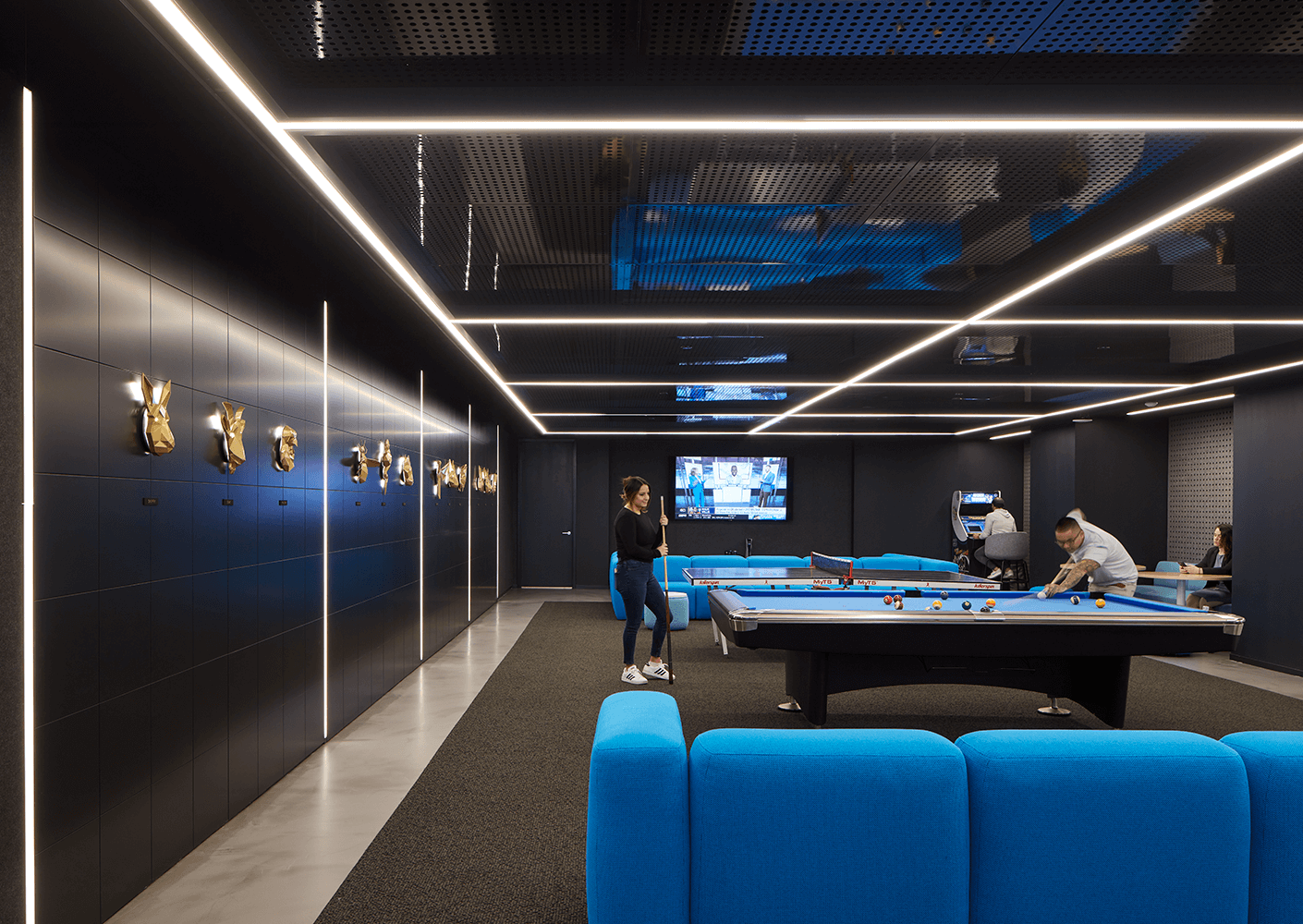 Modern game room with pool table, blue sofas, and wall art.