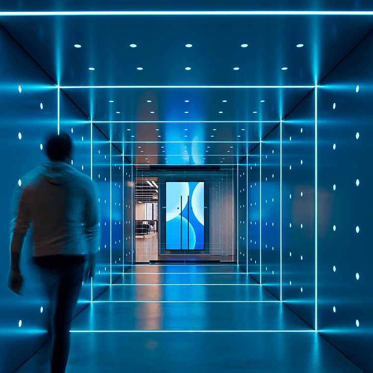 Futuristic blue hallway with illuminated lines and a person walking towards modern art.