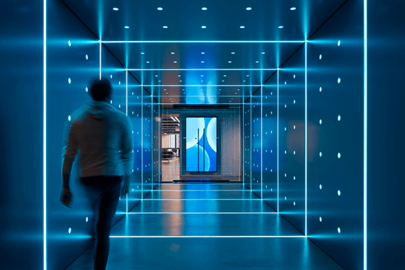 Futuristic hallway with glowing blue lights and walking person.