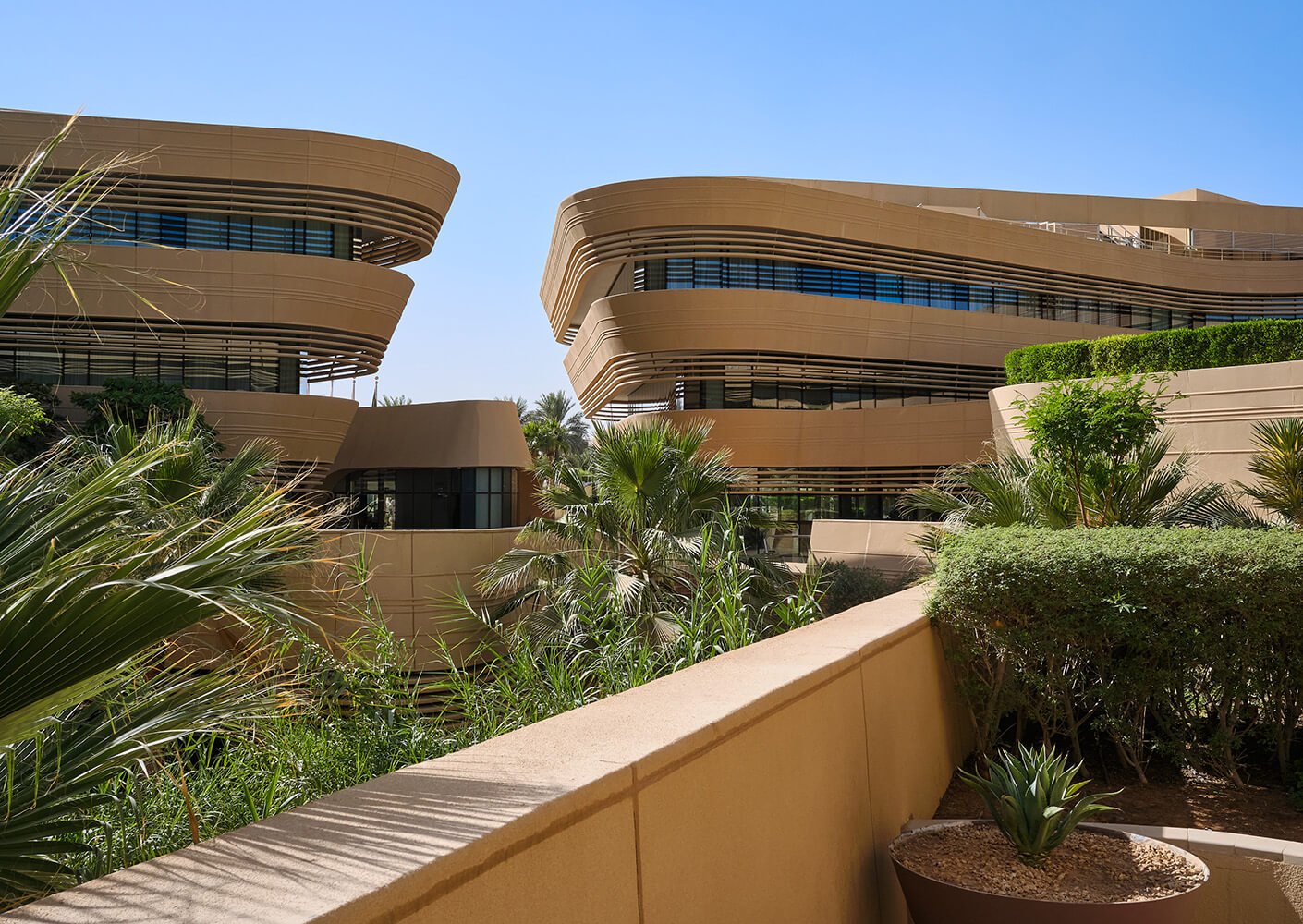 Modern architectural buildings with greenery and blue sky.