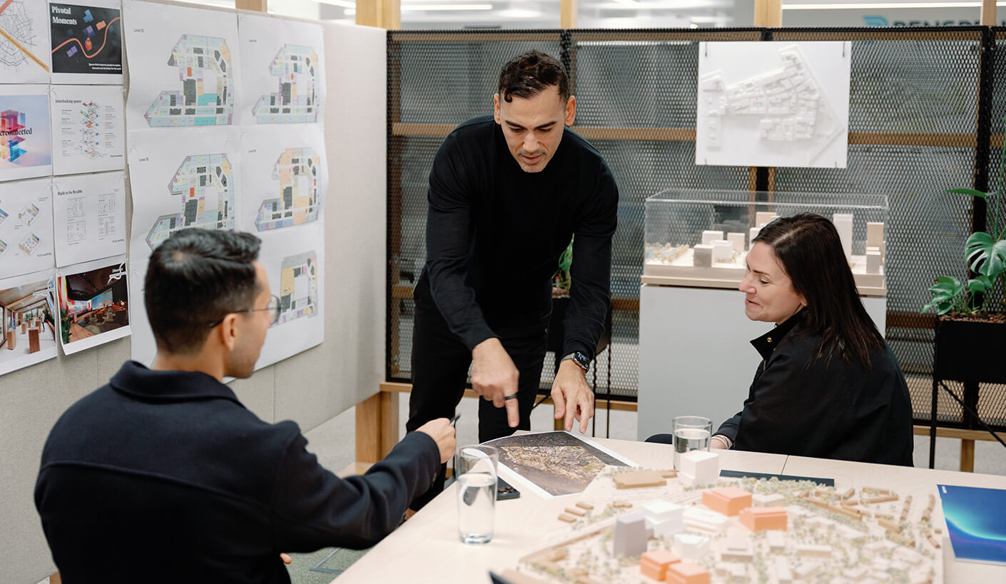 Architects discussing design plans in a modern office with blueprints and a model.