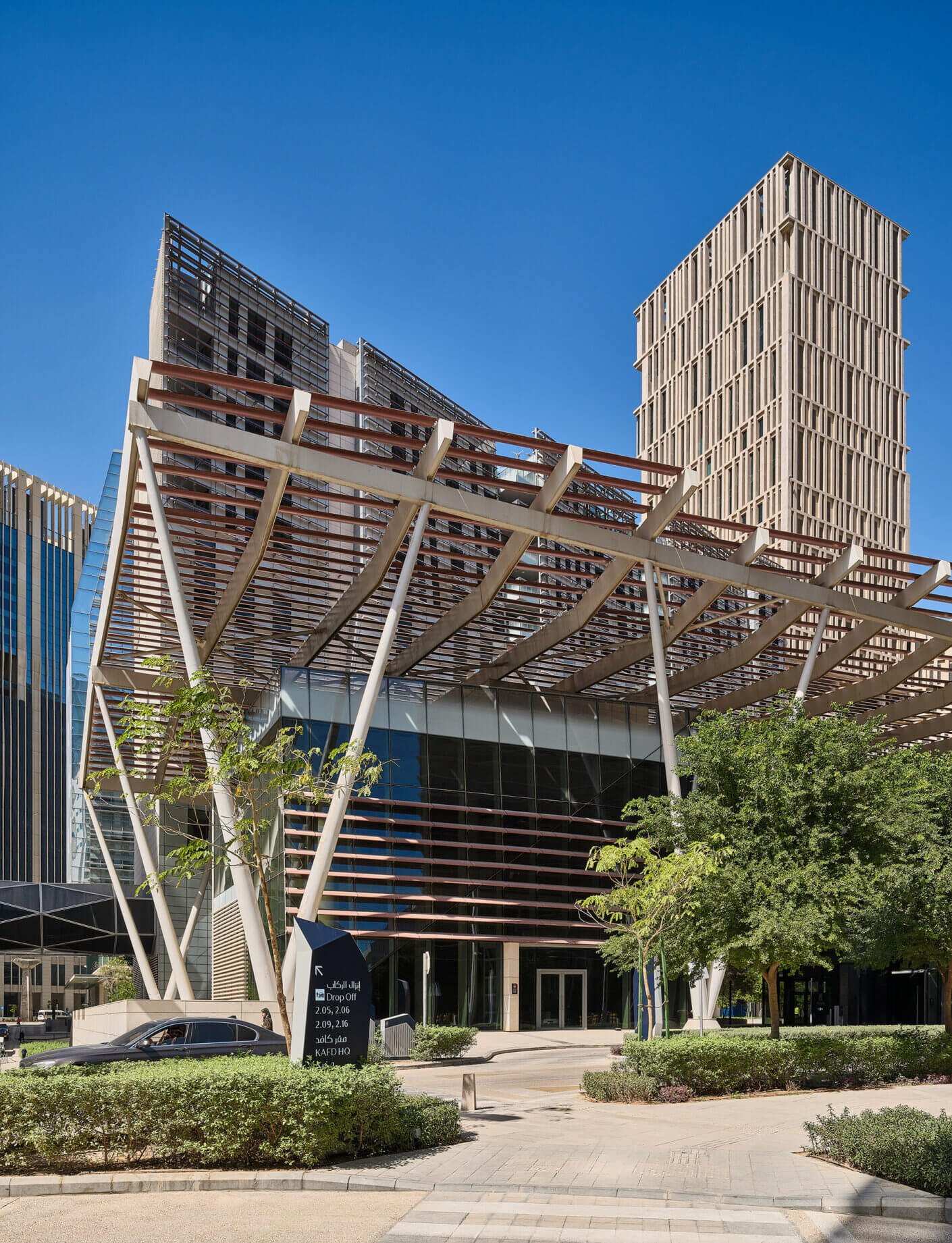 Modern architectural building with unique design and greenery against a clear blue sky.