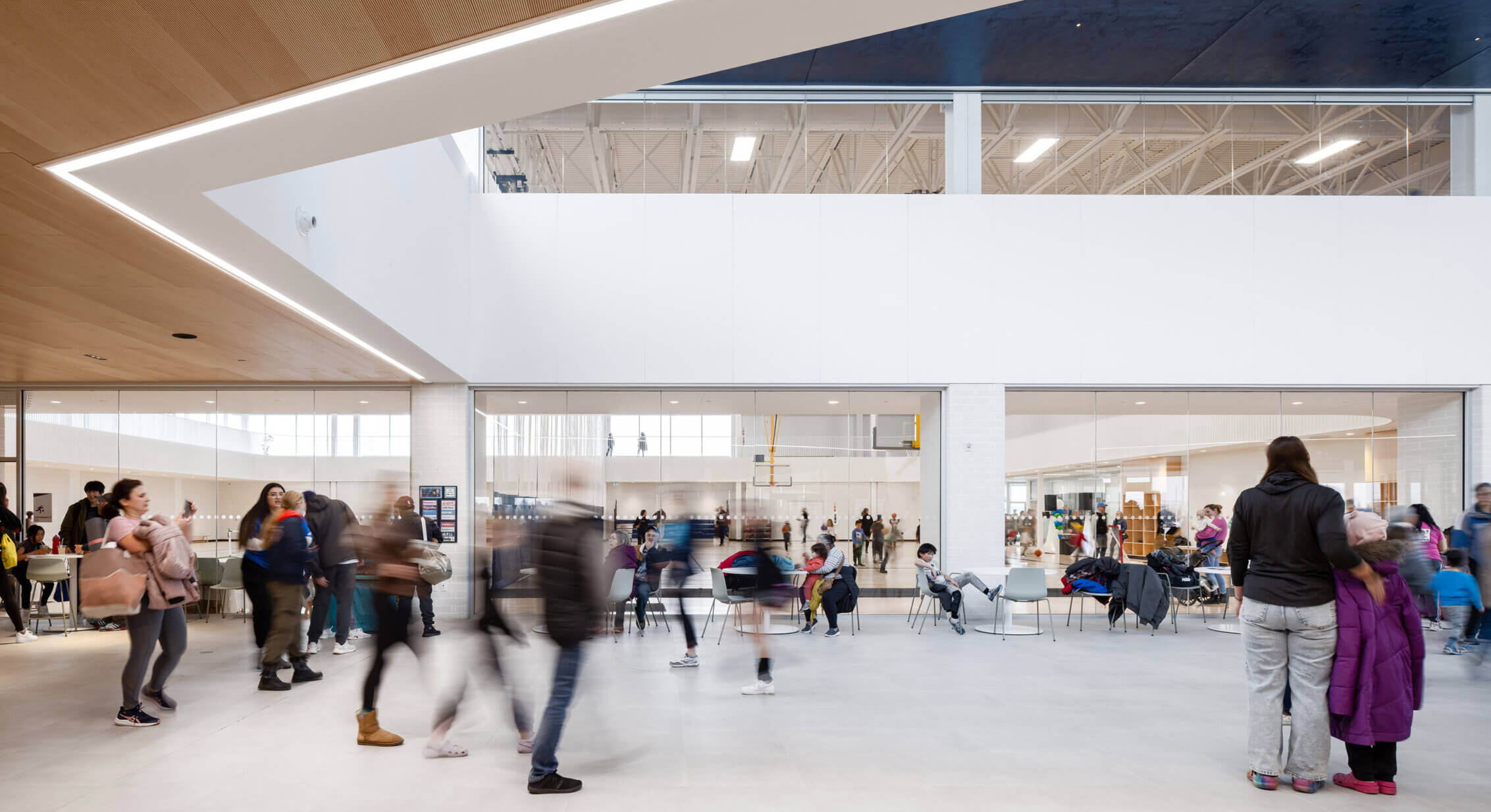 Modern community center interior with people walking and gathering.