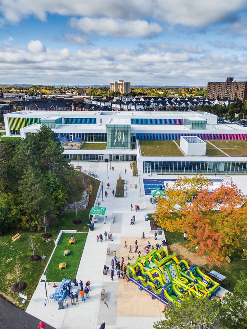 Aerial view of a modern public building with people enjoying a colorful outdoor play area.