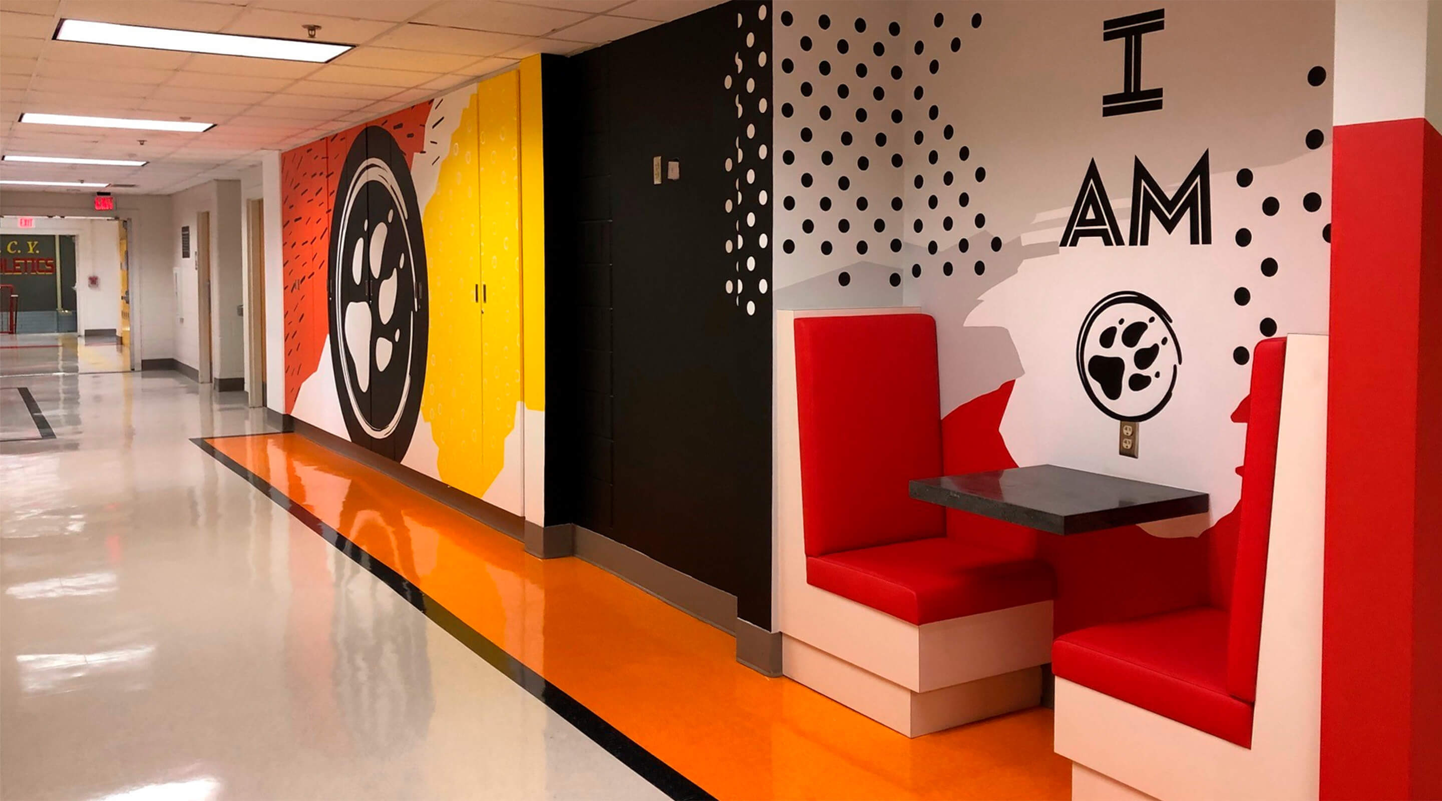 Colorful school hallway with red seating and motivational wall art.