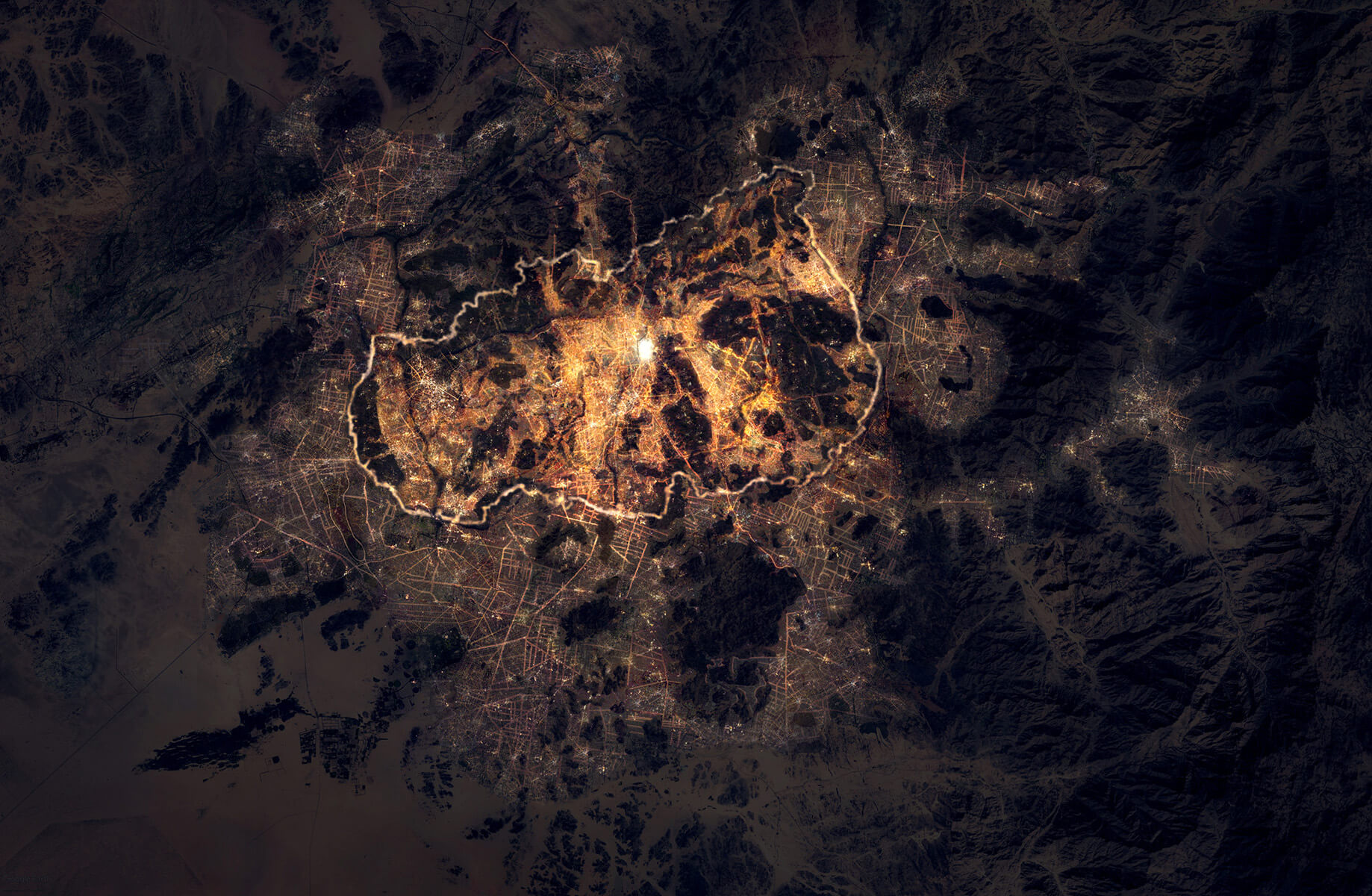 Aerial night view of a brightly lit city, surrounded by darker mountainous terrain.
