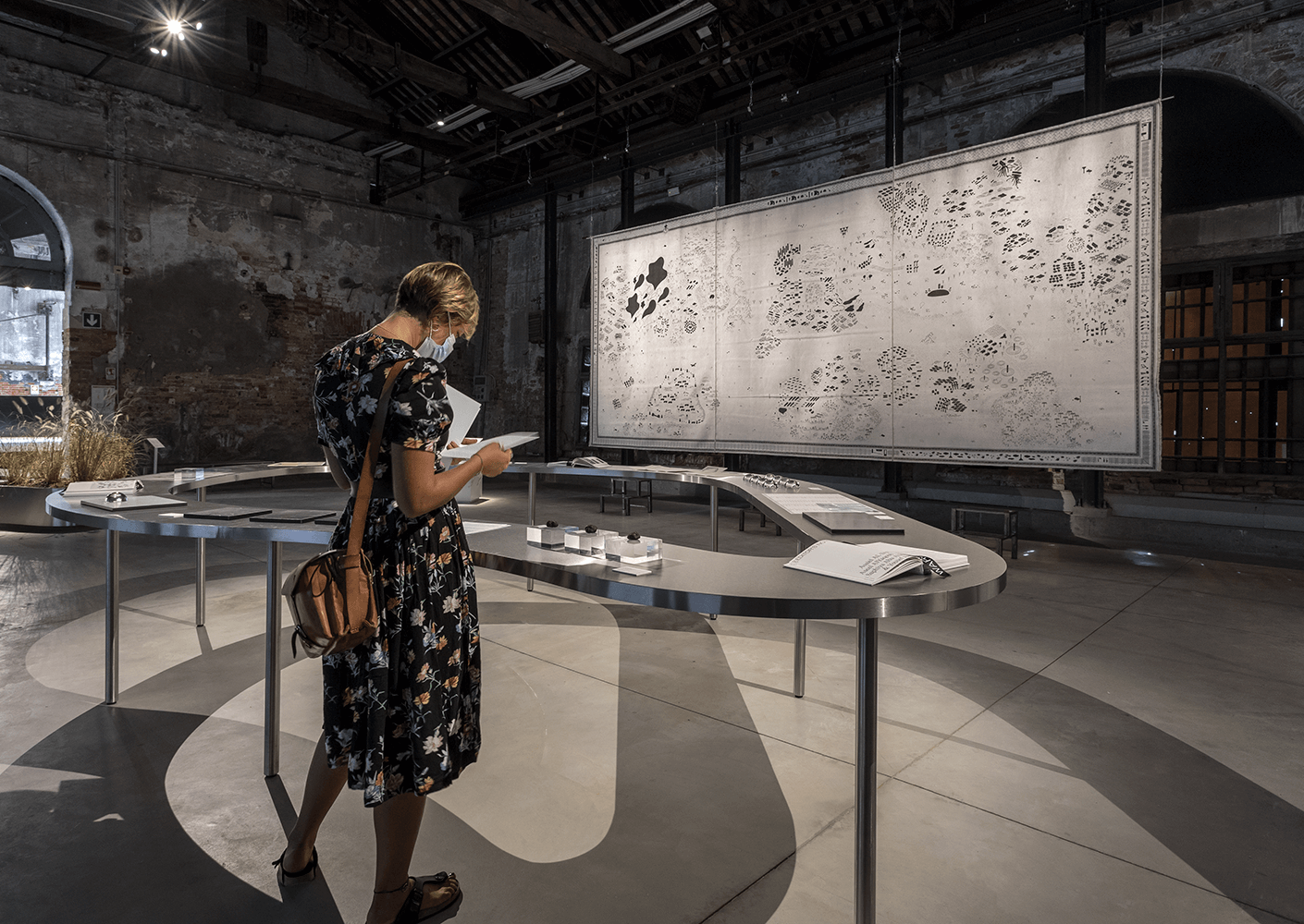 Visitor explores art exhibition with large map on display.