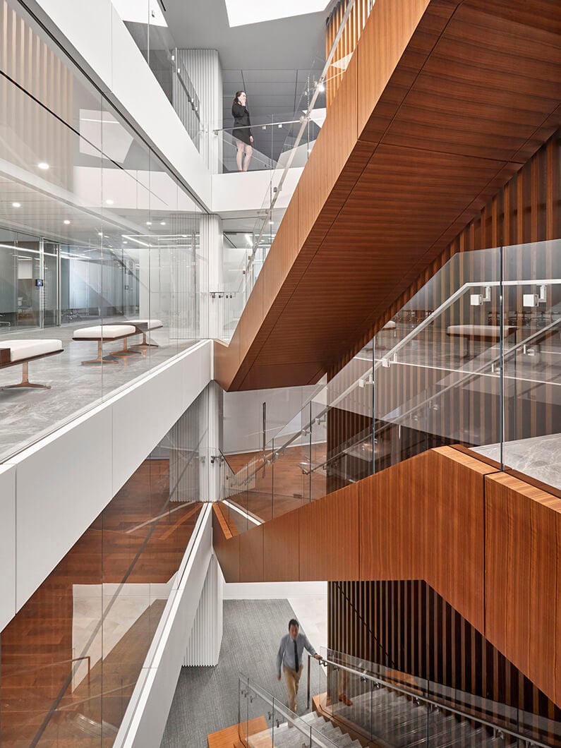 Modern office interior with wooden stairs and glass walls.
