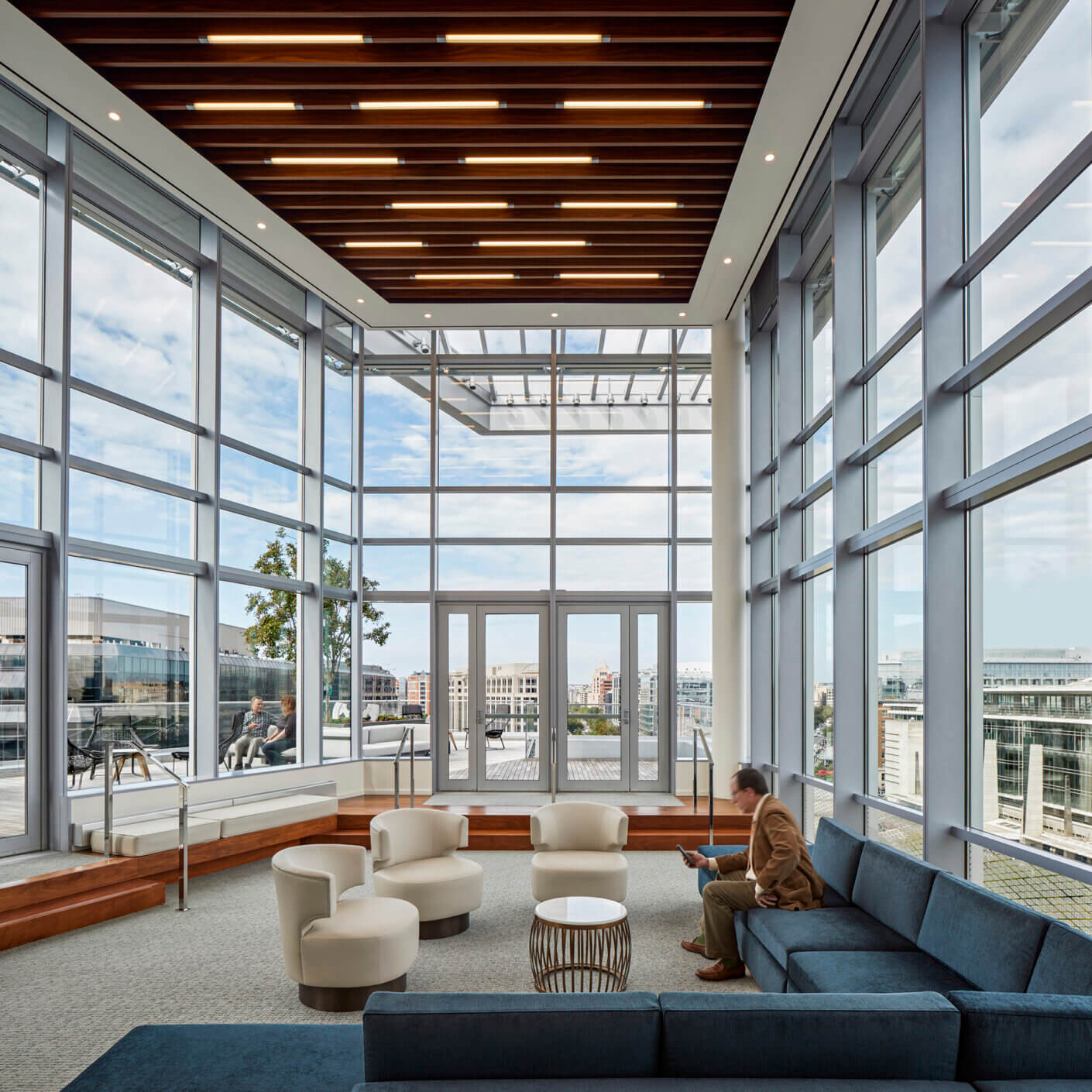 Modern office lounge with large windows and stylish seating.