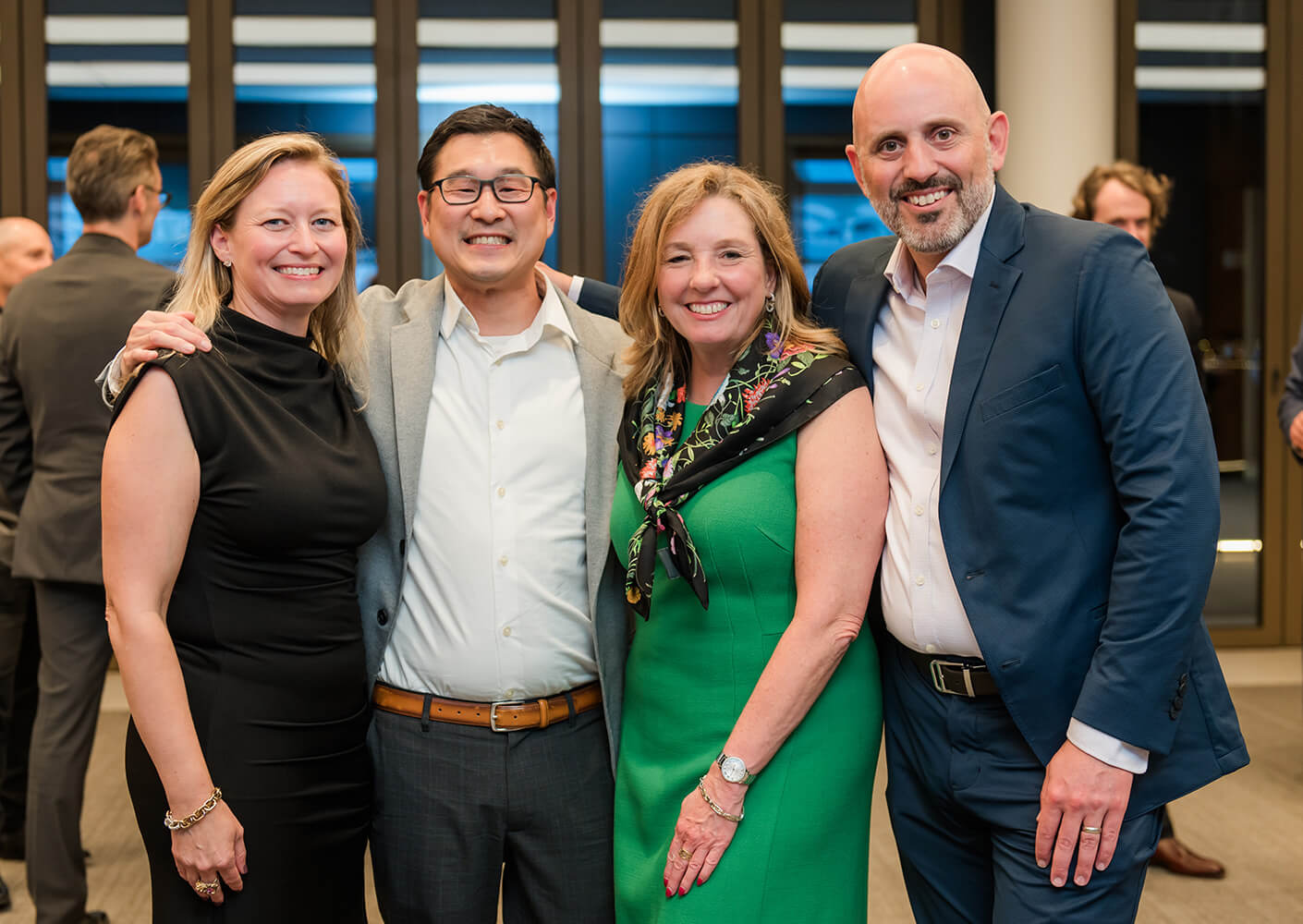 Group of four professionals smiling at a networking event.