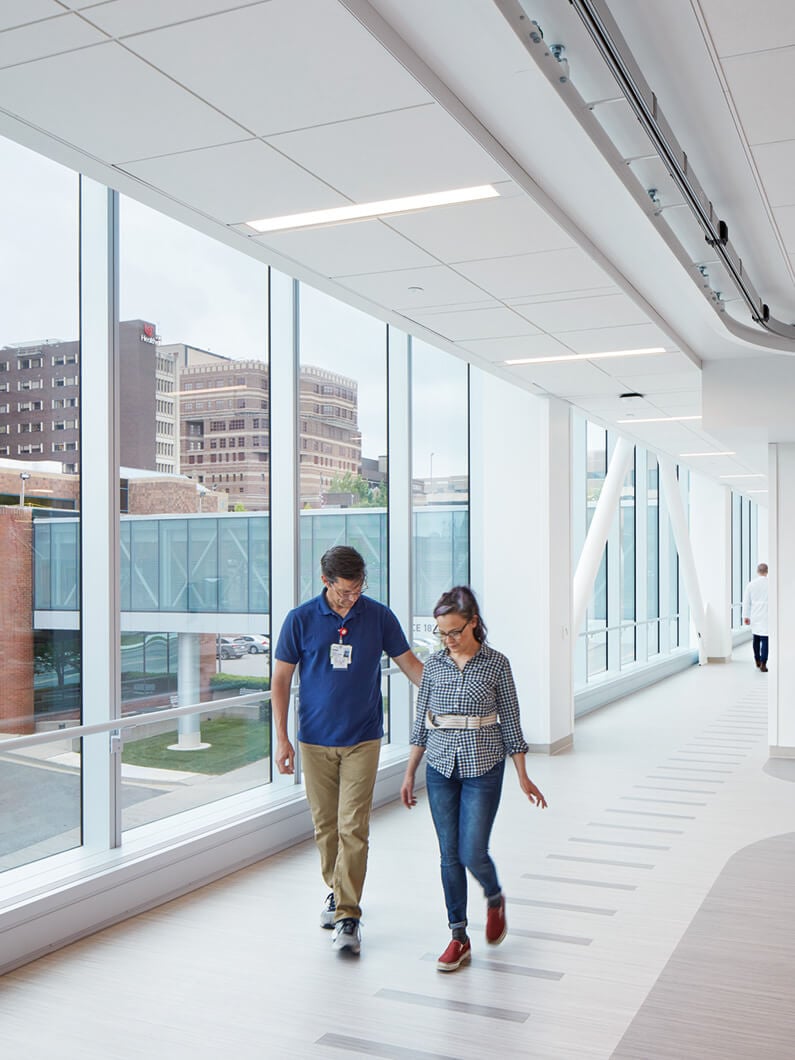 Two people walking in a modern hospital corridor.