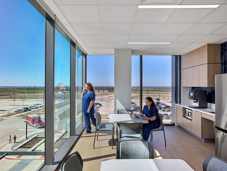 Modern medical break room with panoramic windows and healthcare professionals.