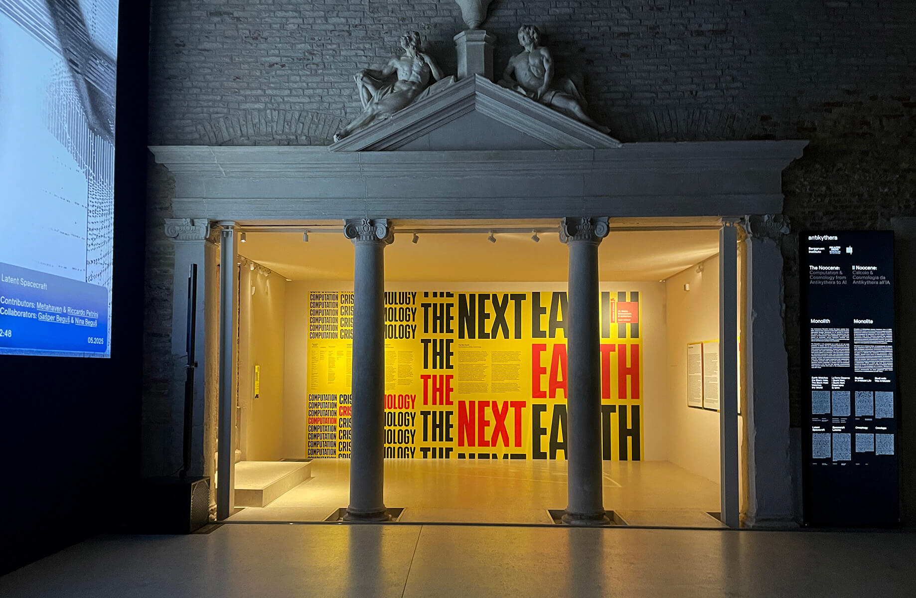Exhibition entrance with bold The Next Earth text on yellow and red background.