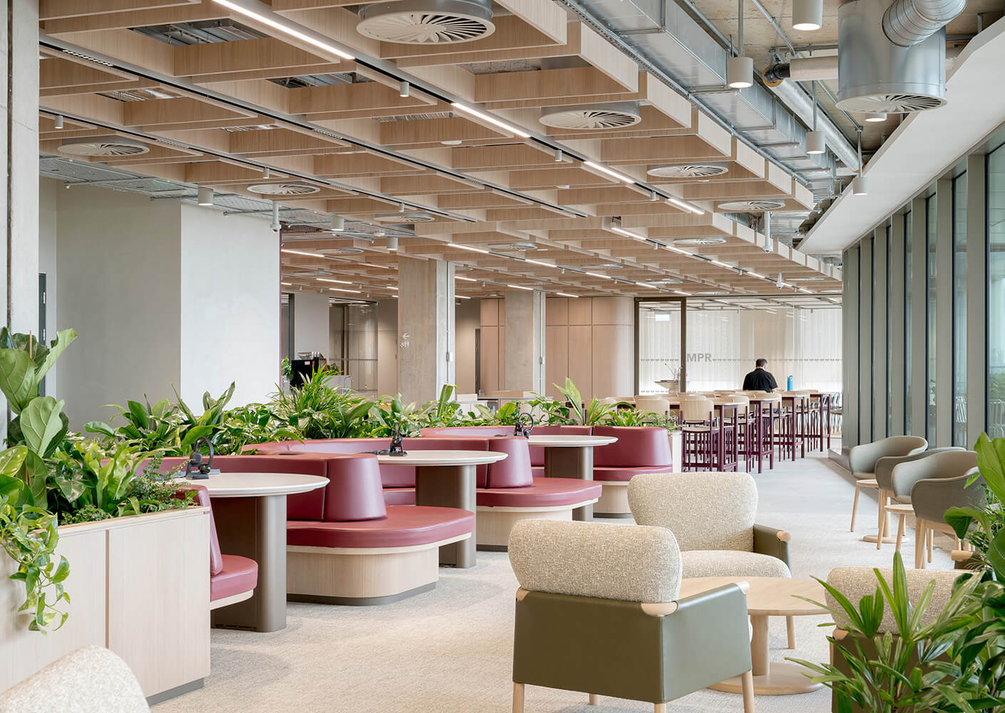 Modern office lounge with plants, seating, and natural light.