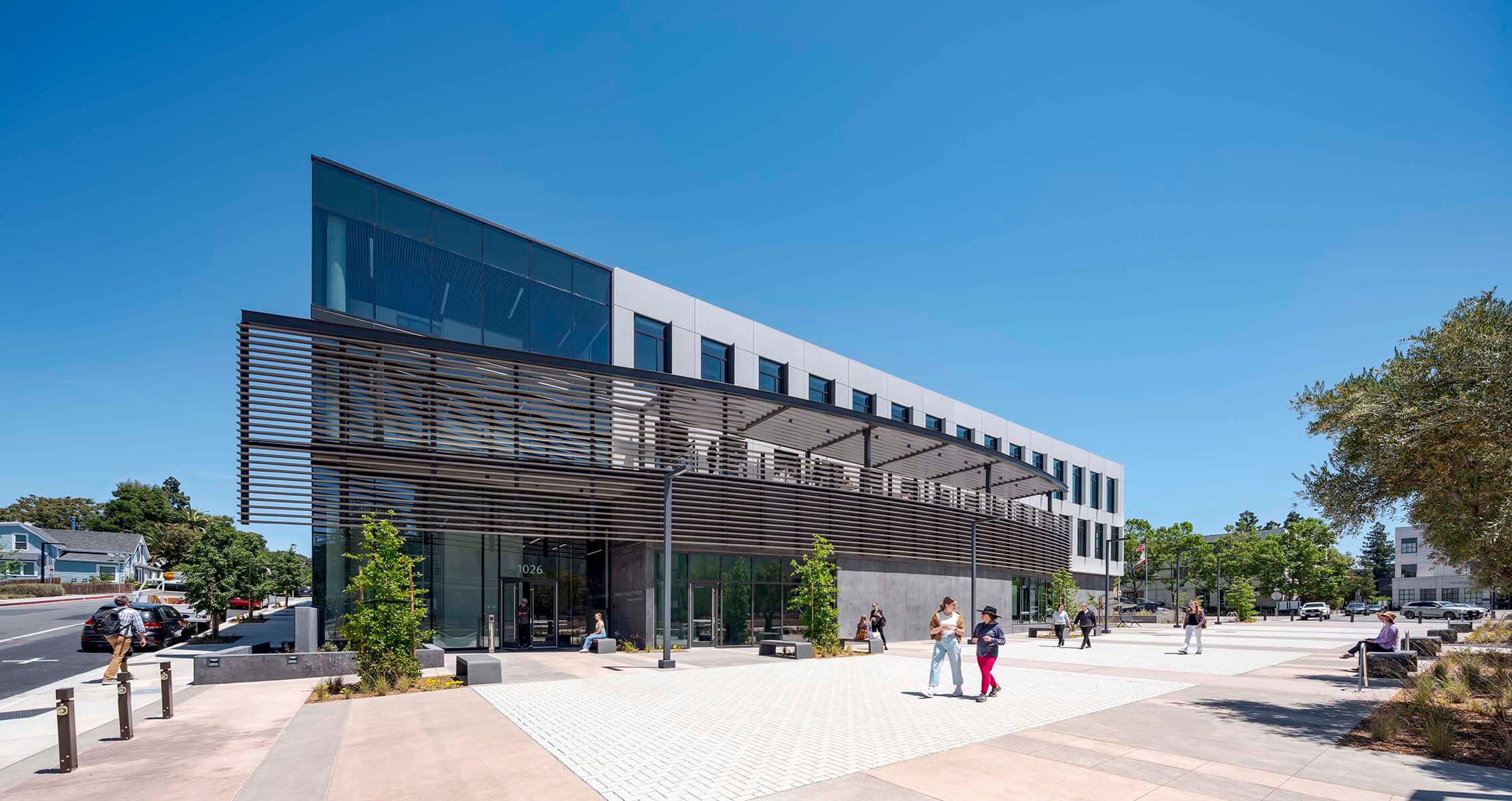 Modern office building with glass facade under clear blue sky.
