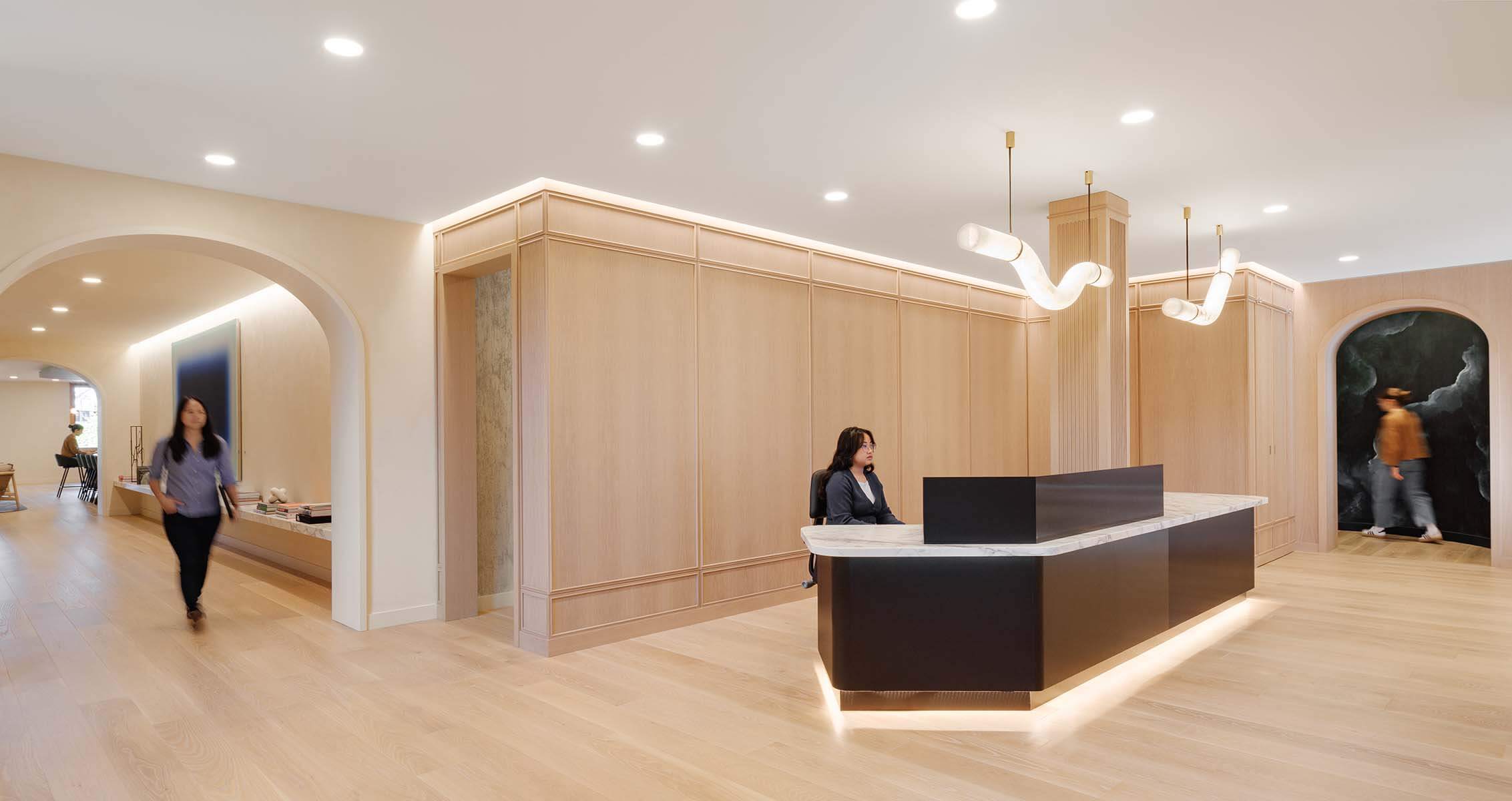Modern office reception area with wood decor and lighting fixtures.