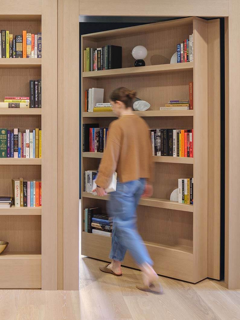 Hidden door bookshelf with person walking through secret passage.