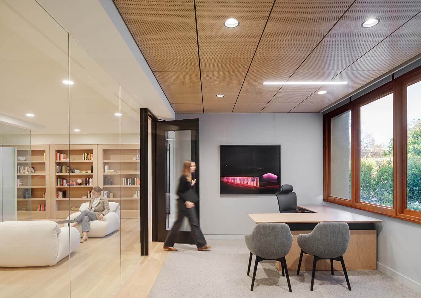 Modern office with glass walls, sleek furniture, and natural light.