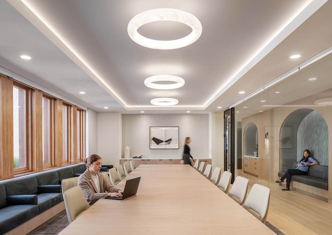 Modern conference room with people working and sleek lighting fixtures.