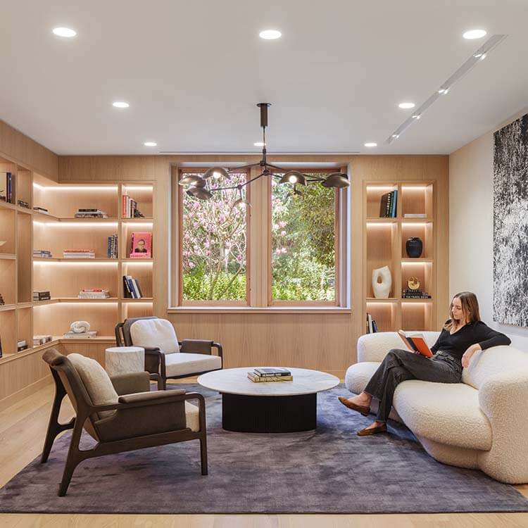 Modern living room with cozy seating, bookshelves, and natural light.