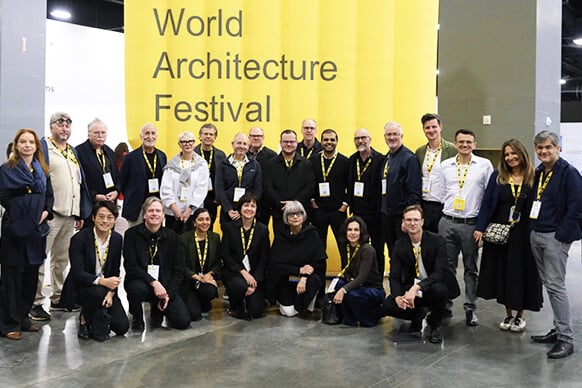 Group at World Architecture Festival 2023 in front of a bold yellow banner. 