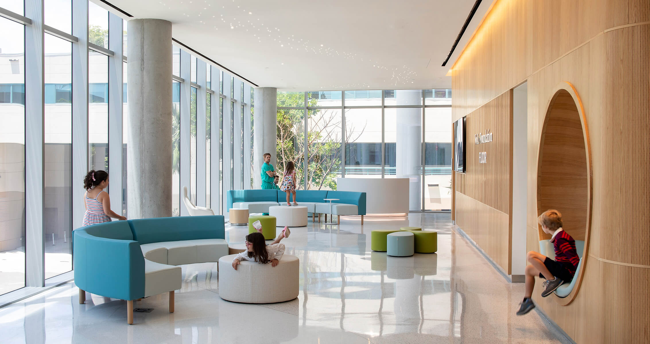 Children play in a modern hospital interior with rounded furniture and large windows