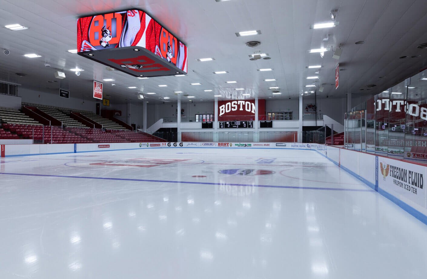 Indoor ice hockey rink with Boston University signage and empty seats.