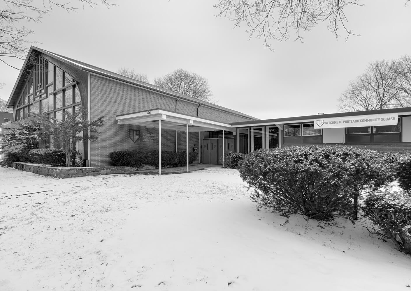 Existing conditions of former brick building in winter, entrance to Portland Community Squash.