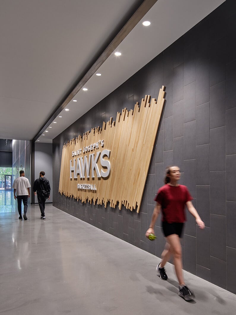 Hallway with Saint Joseph's Hawks basketball sign, and students walking by.