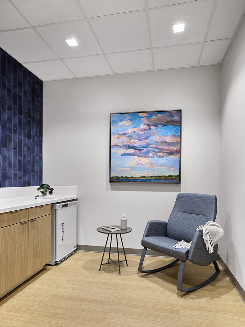 Modern room with blue chair, artwork, and side table.