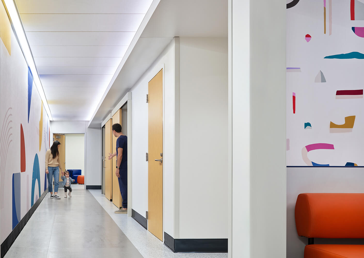 Contemporary hallway with colorful abstract art and people walking.