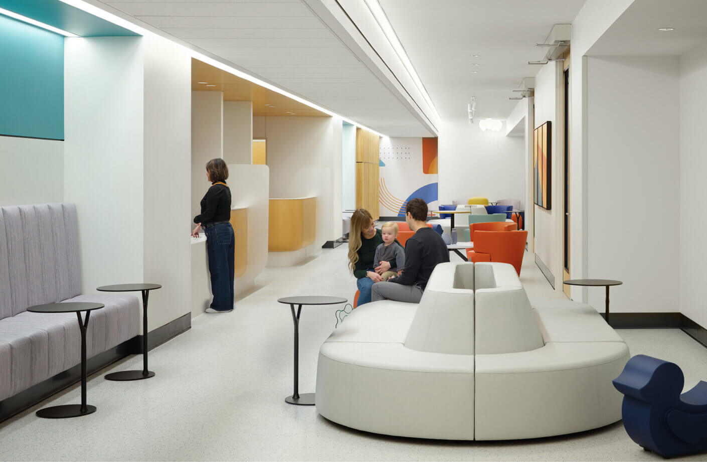 Modern waiting room with colorful seating and people interacting.