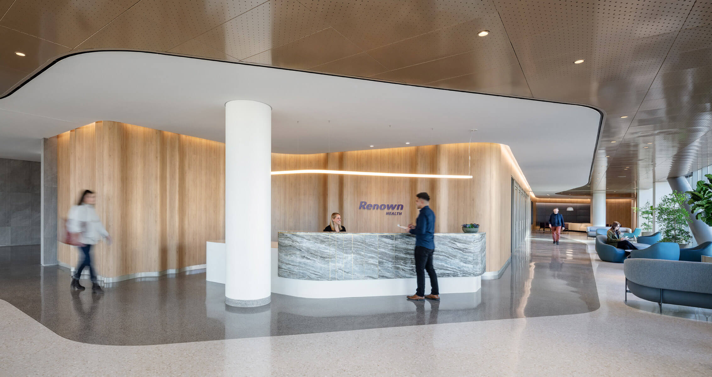 Modern reception area with a curving wood backdrop and people in a bright, spacious lobby.