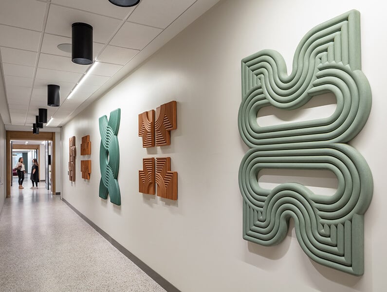 Abstract wall art in a modern hallway with two people in the background.