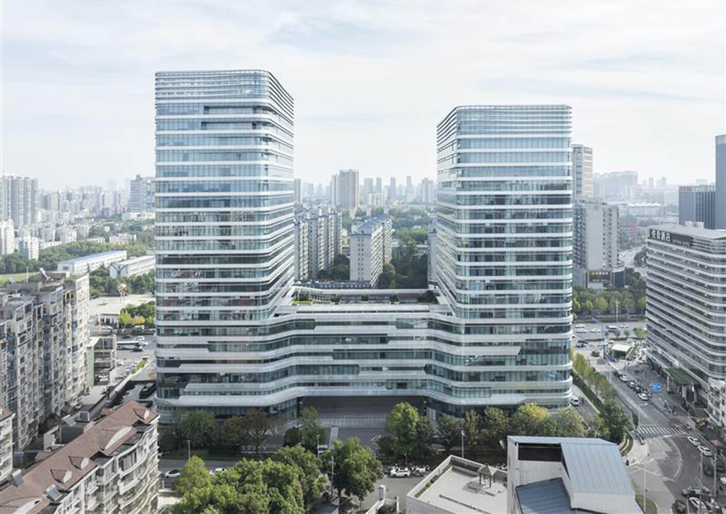Modern cityscape with two tall, sleek glass buildings under a clear sky.