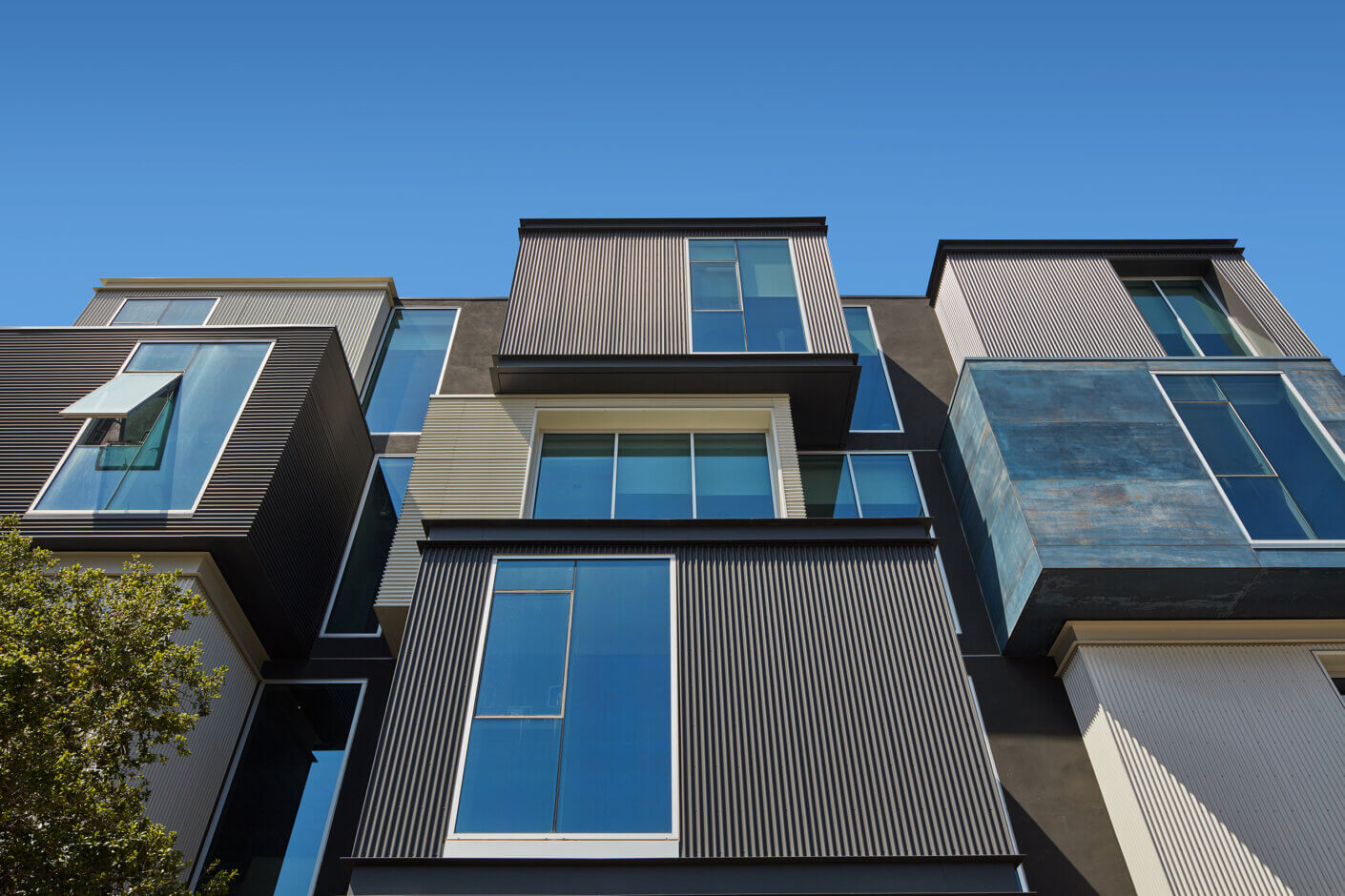Modern building with large windows and geometric design against a clear blue sky.