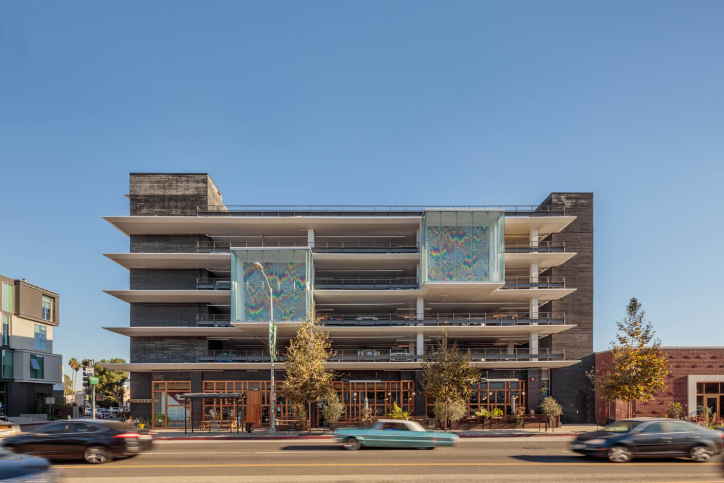 Modern multi-story building with artistic panels on a busy street.