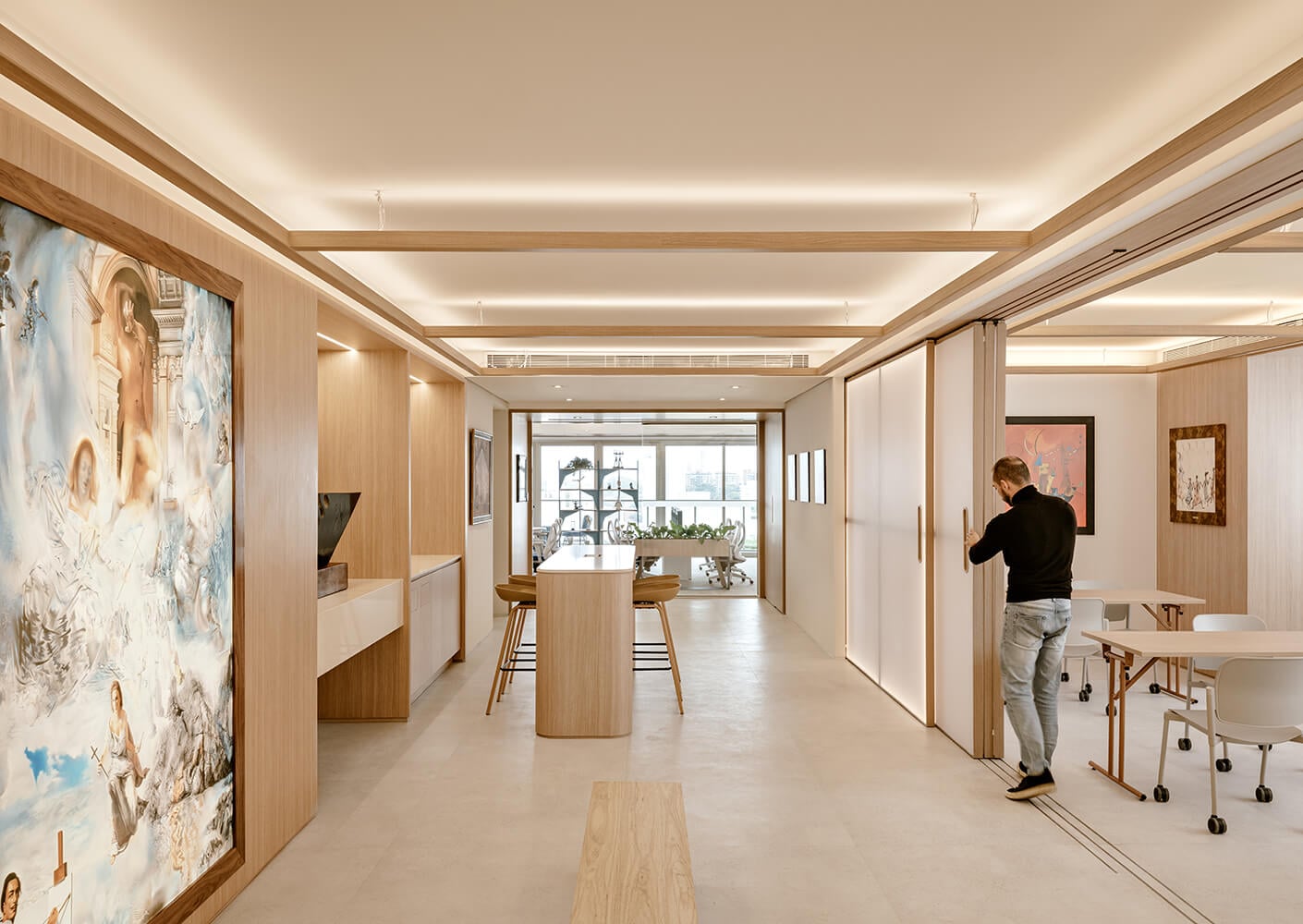 Modern office space with artwork, sliding doors, and a person adjusting the partition.
