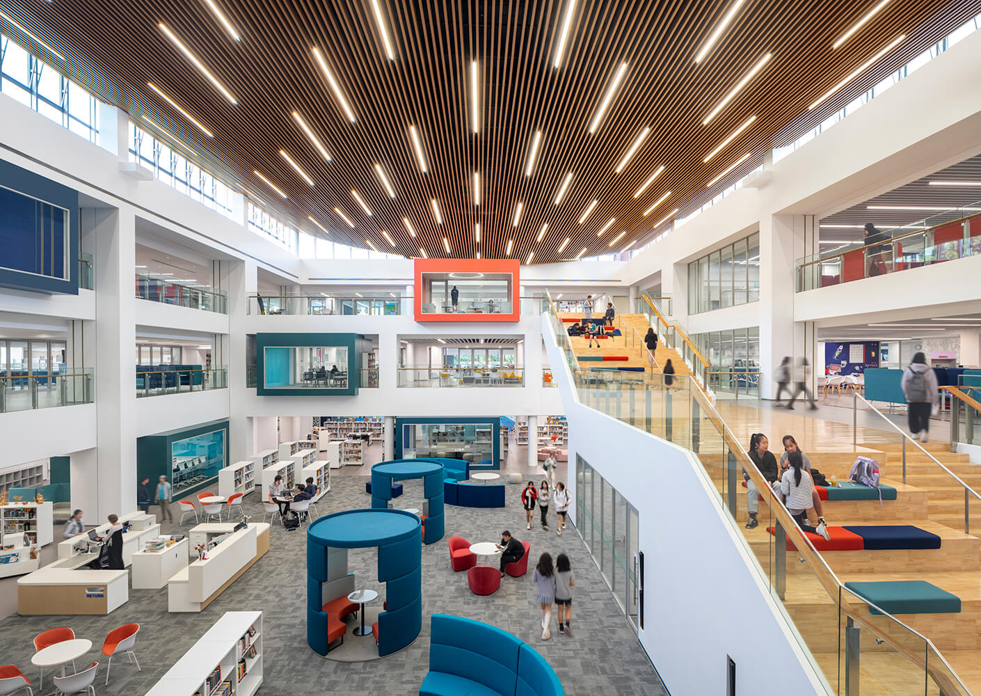 Modern library interior with students, study areas, and vibrant design elements.