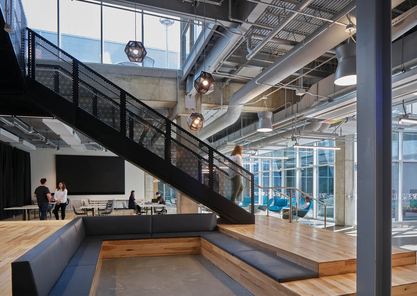 Modern open office space with staircase, people meeting, and contemporary furniture.