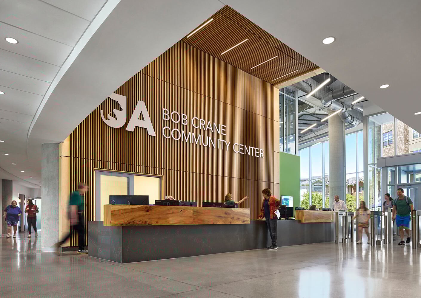 Modern community center interior with reception desk and visitors.