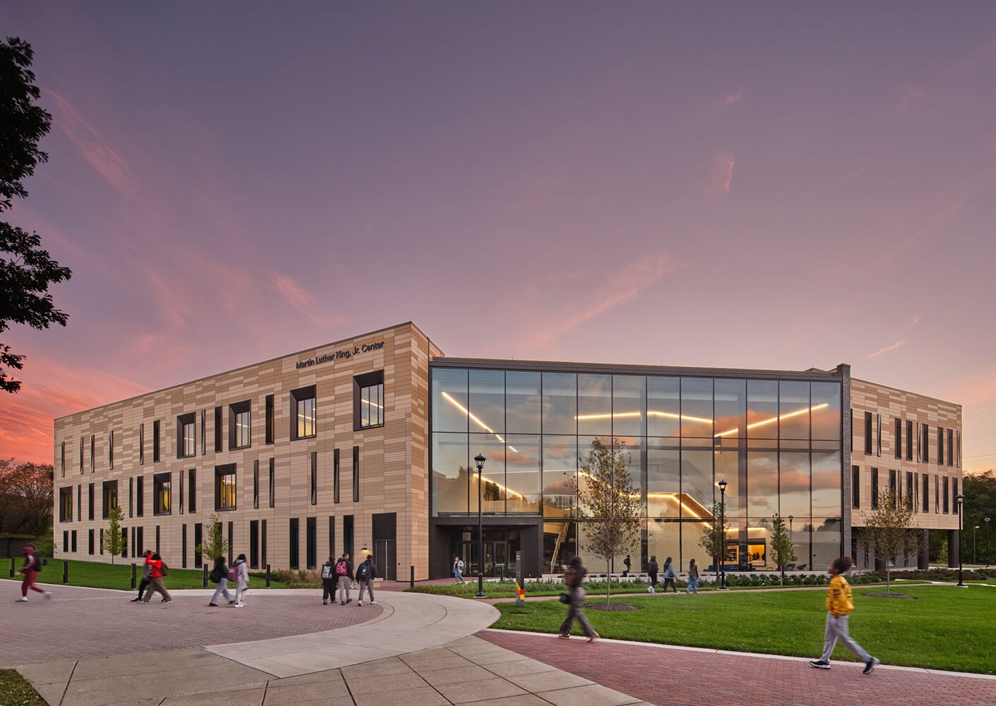 Modern educational building at sunset with people walking.