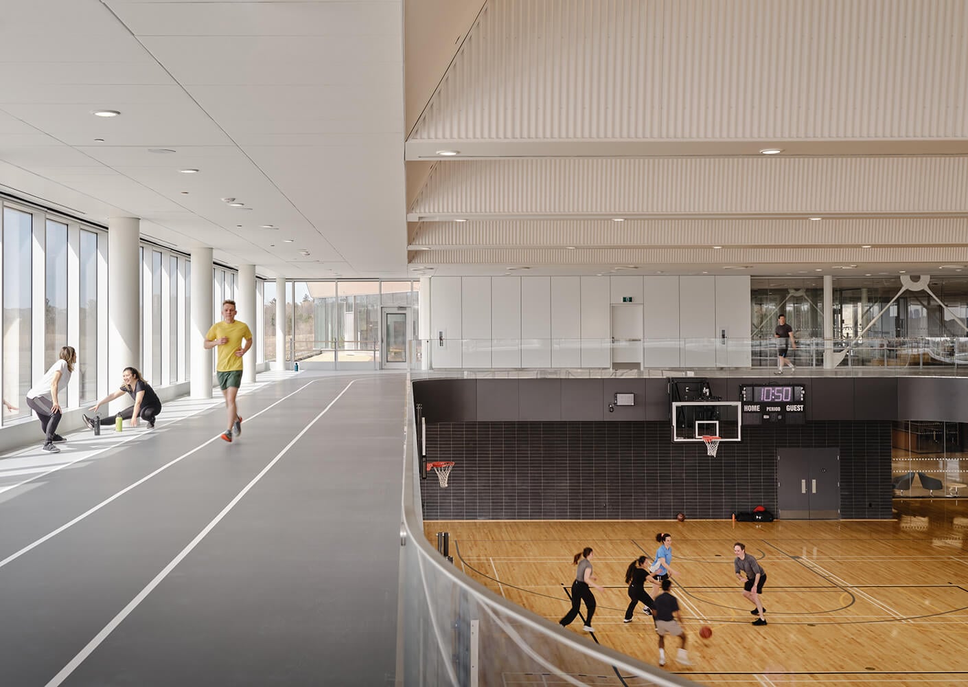 Indoor sports facility with jogging track and basketball game in progress.