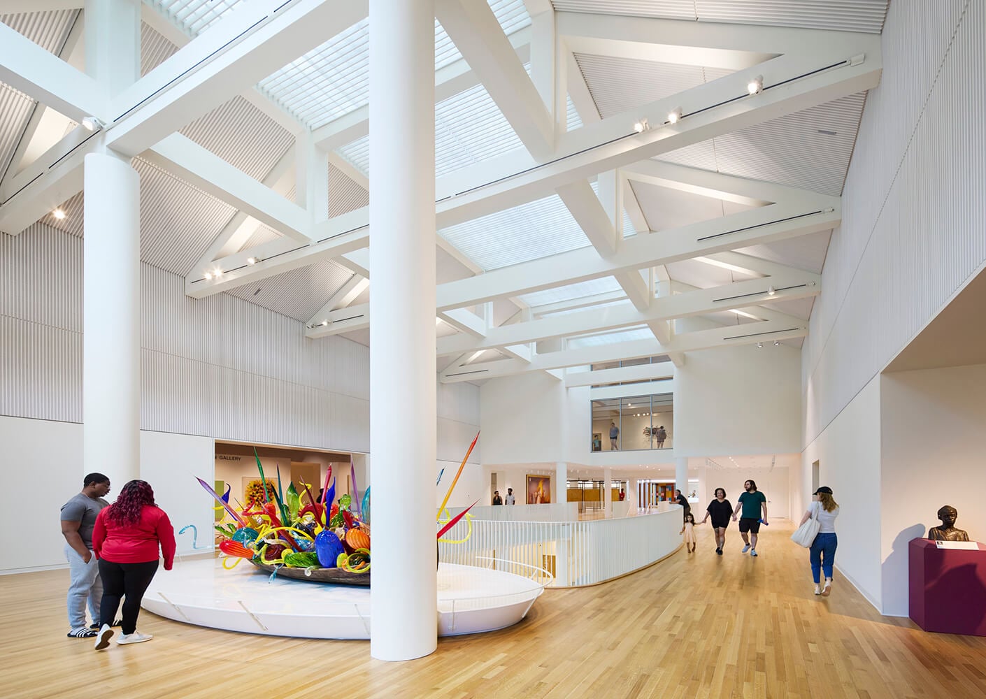 Modern art gallery interior with colorful sculpture and visitors exploring exhibits.