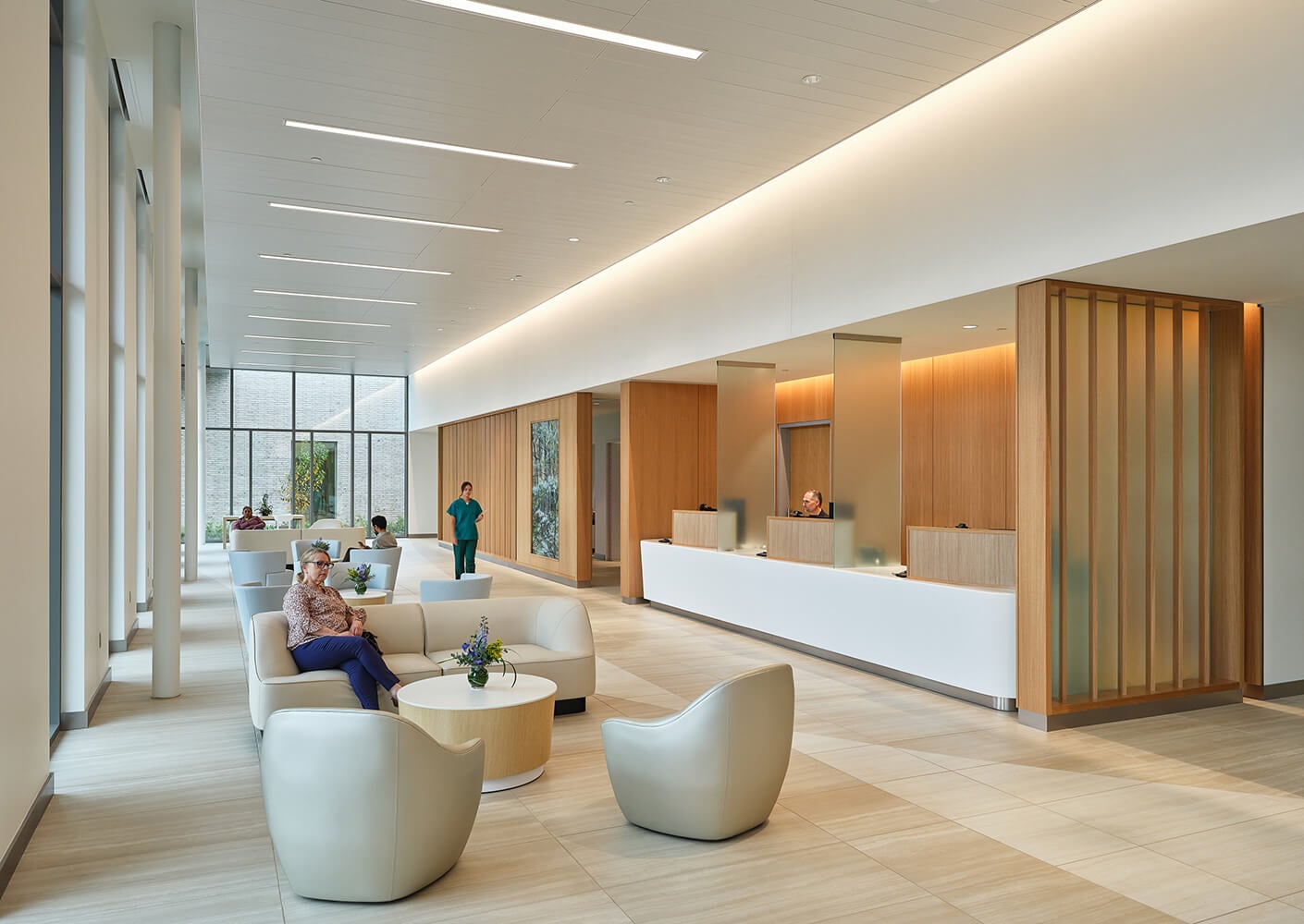 Modern hospital reception area with seating and staff at the counter.