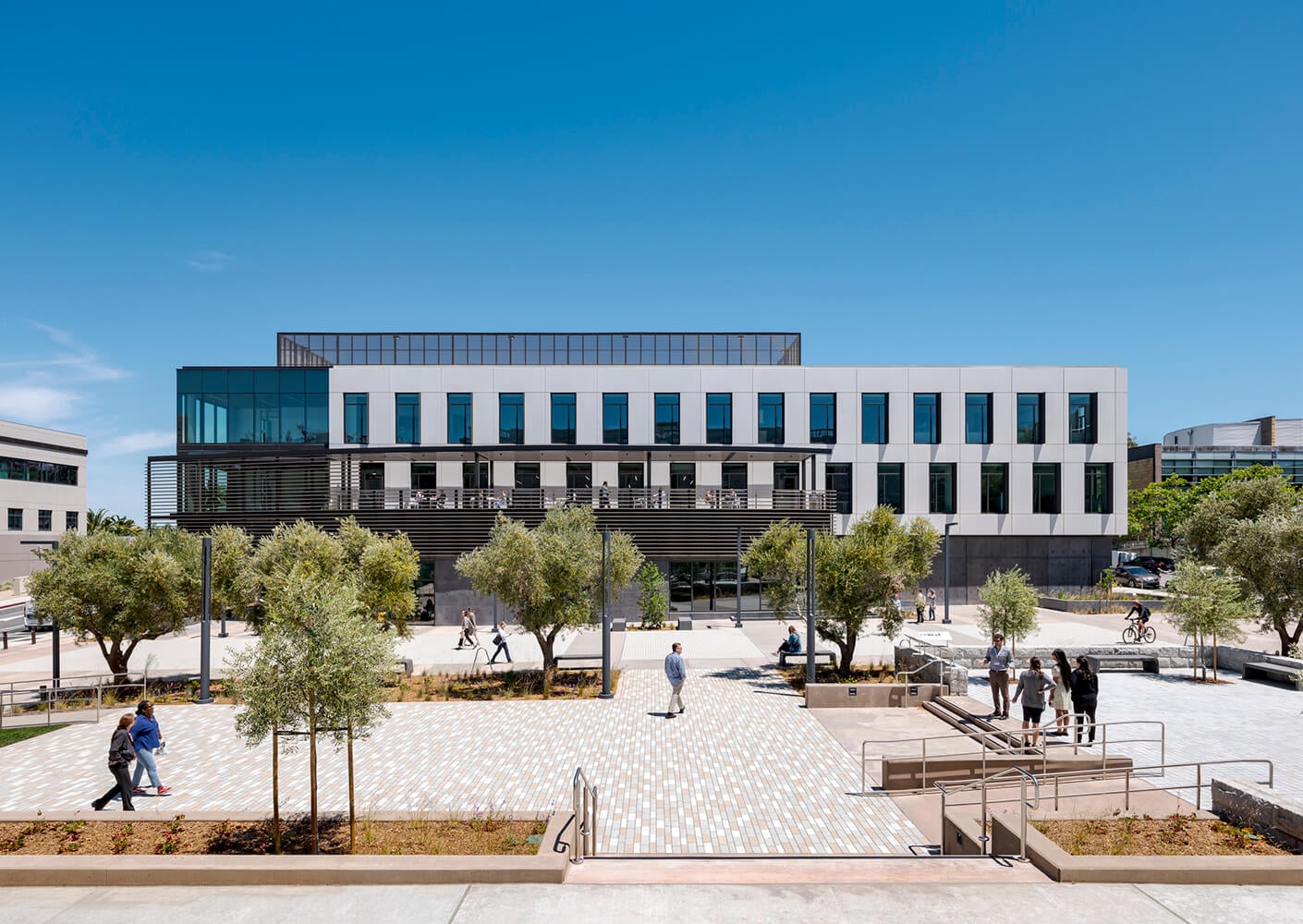 Modern office building with large windows and trees on a sunny day.