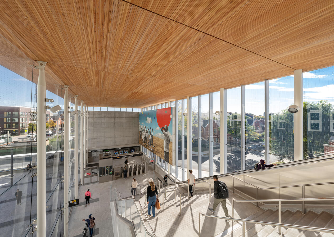 Modern train station interior with wooden ceiling and artistic wall mural.