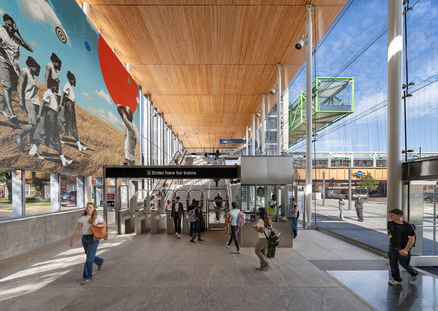 Modern train station interior with passengers and colorful mural art.