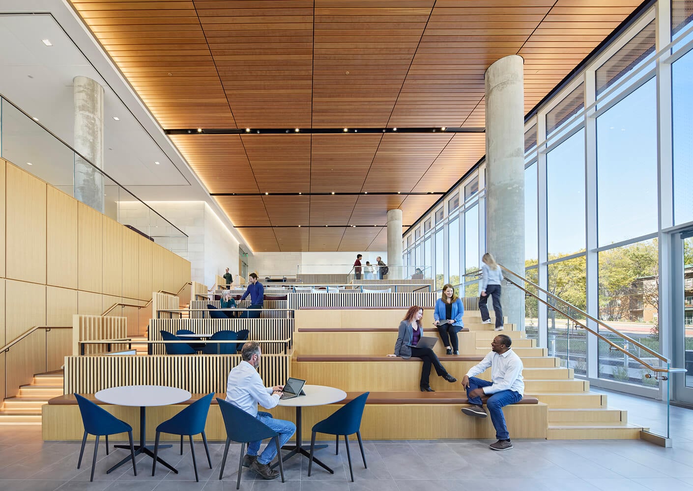 Modern open office space with people collaborating on tiered seating.